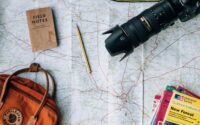 flat lay photography of camera, book, and bag